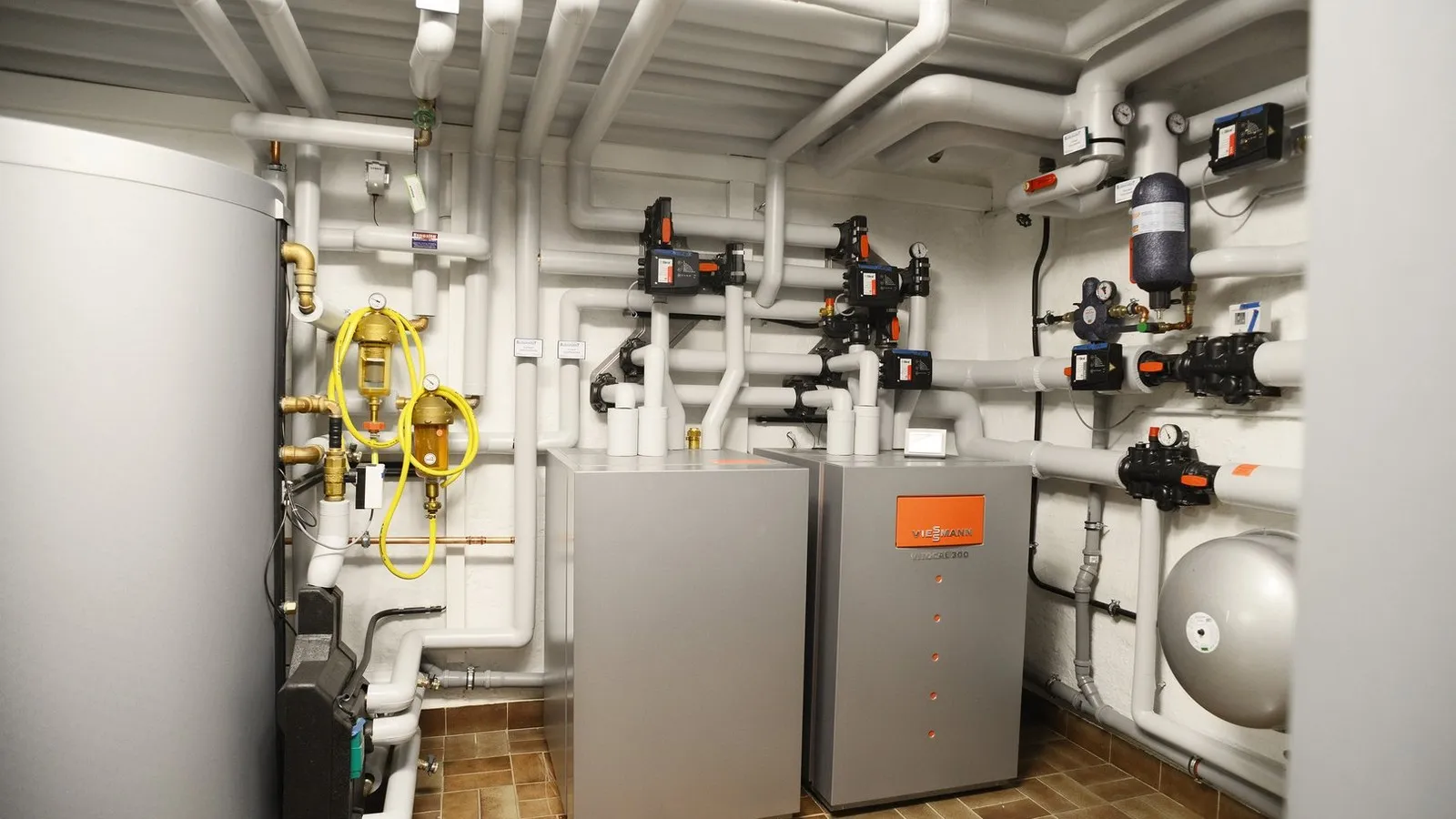 Ein Wärmepumpe und mehrere Rohre, die von der Wärmepumpe wegführen und an der Decke des Raums verlaufen. 
